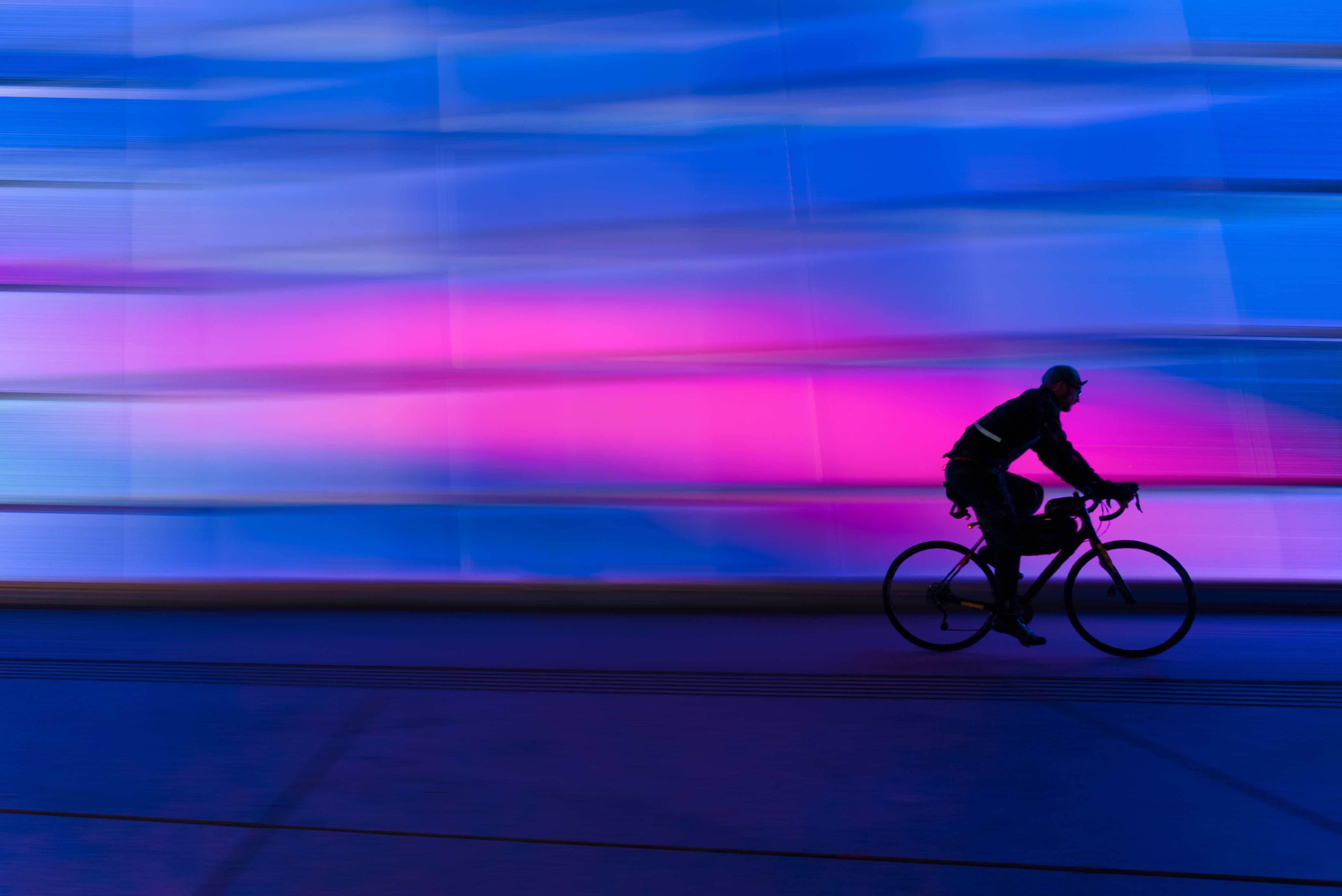 A cyclist riding in front of moody lighting